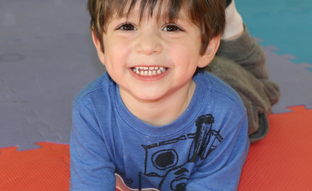 Child smiling while lying on a colorful mat