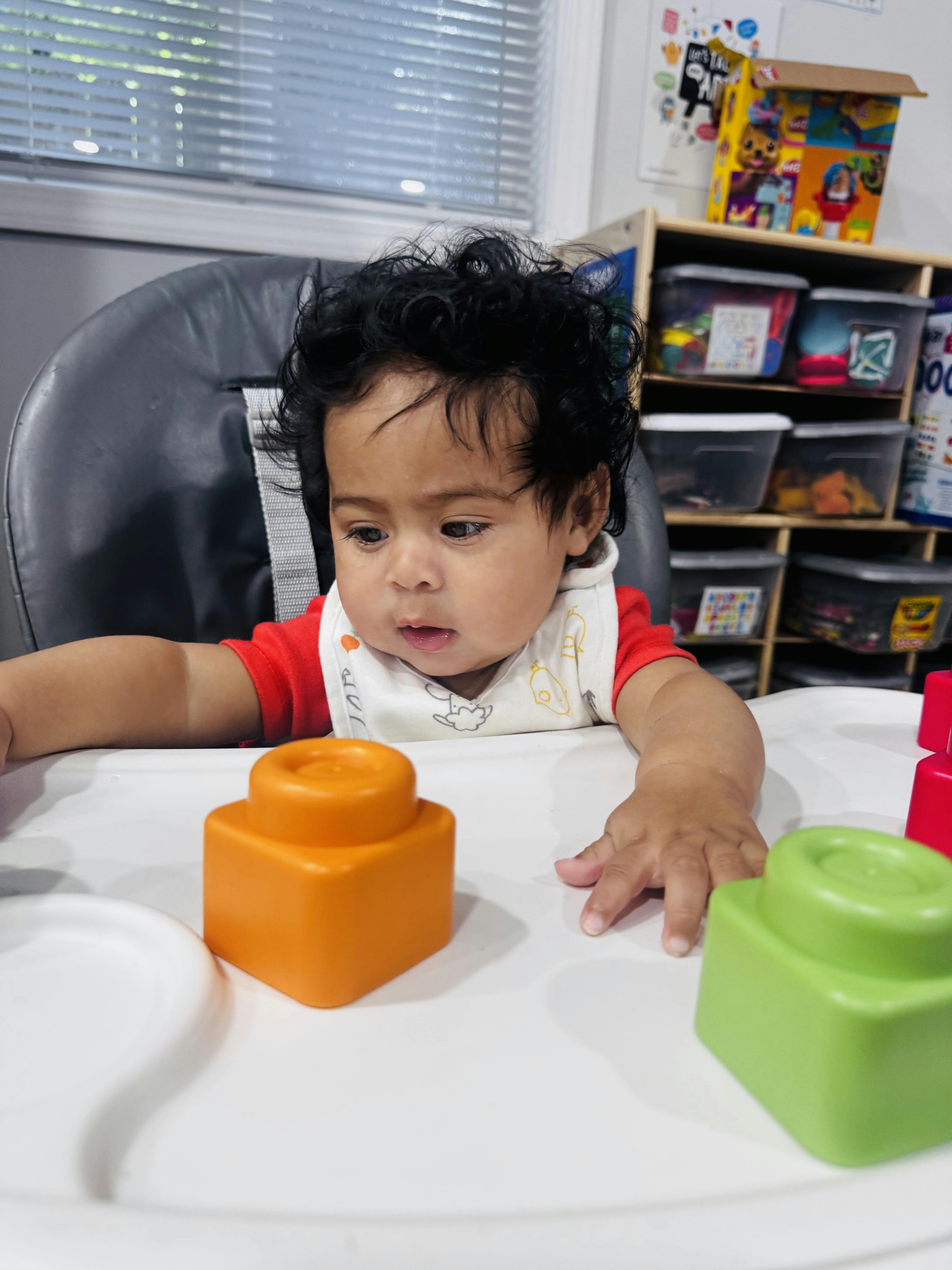Child in a high chair with building blocks on the tray