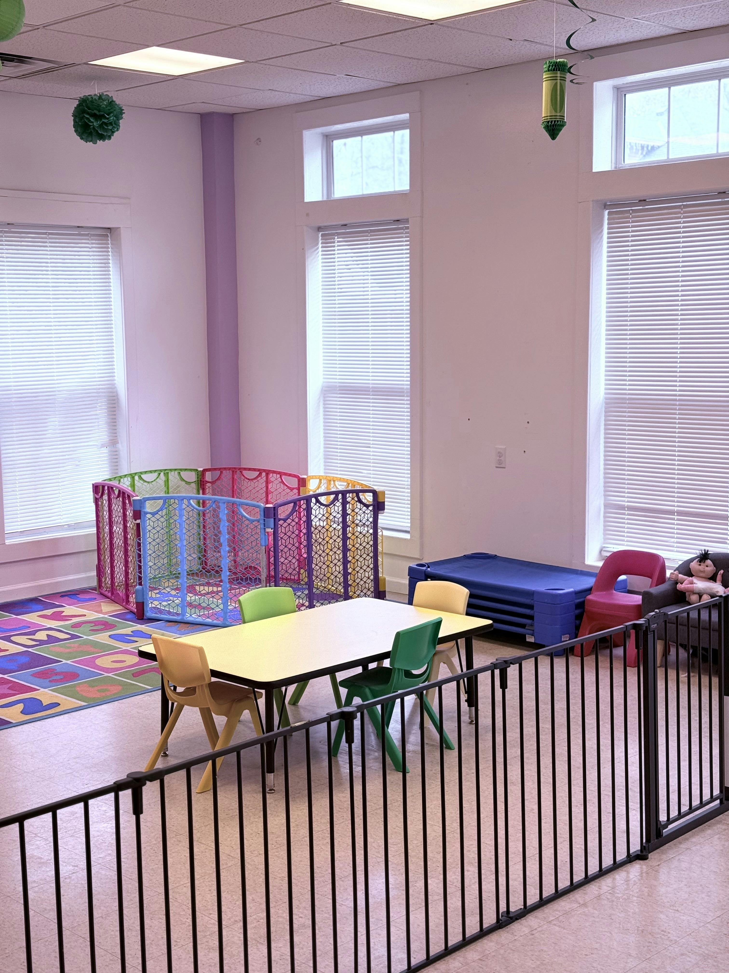 Children's play area with a colorful playpen, small table, and chairs