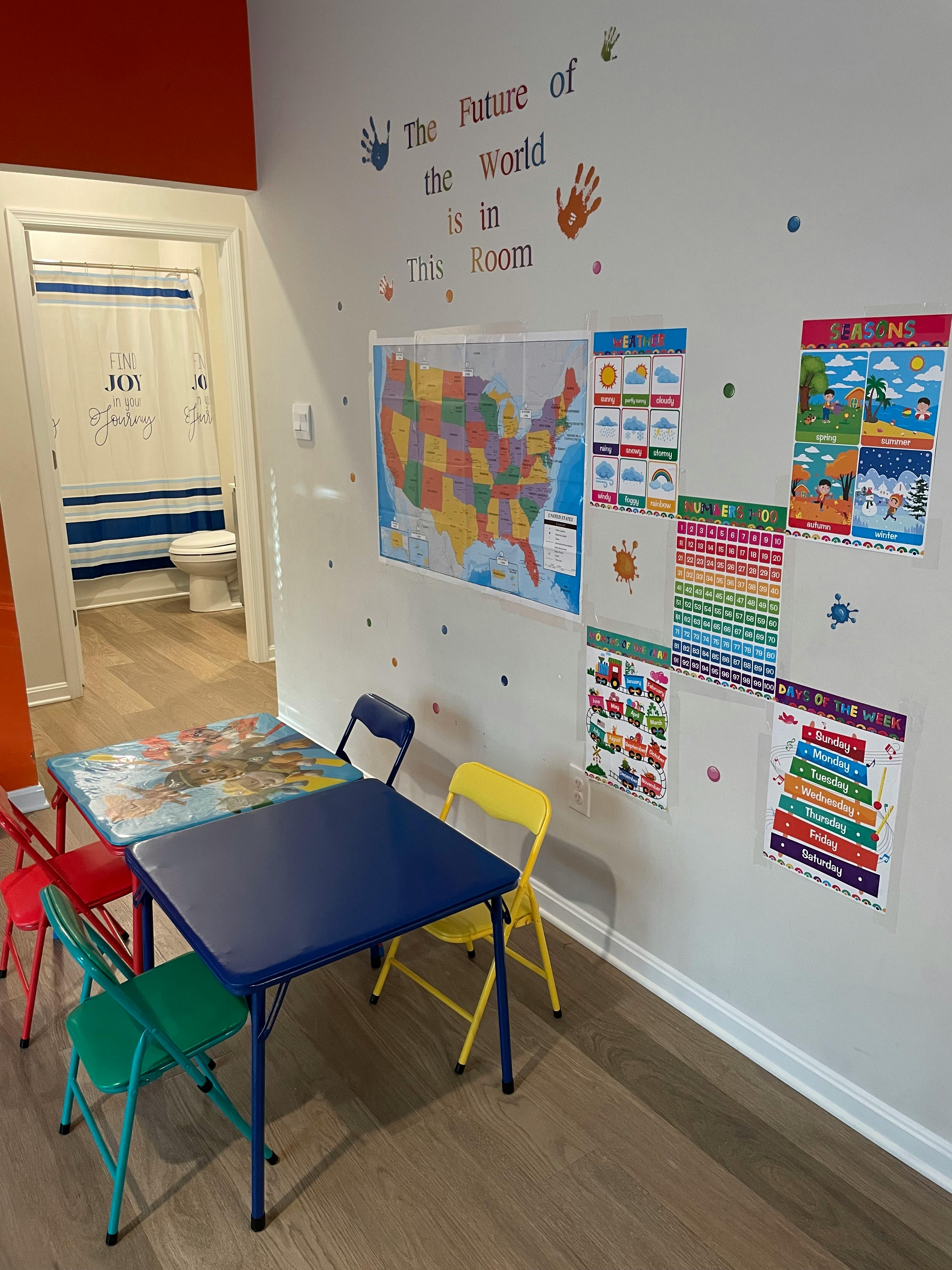 Classroom with small tables and chairs, educational posters on the wall