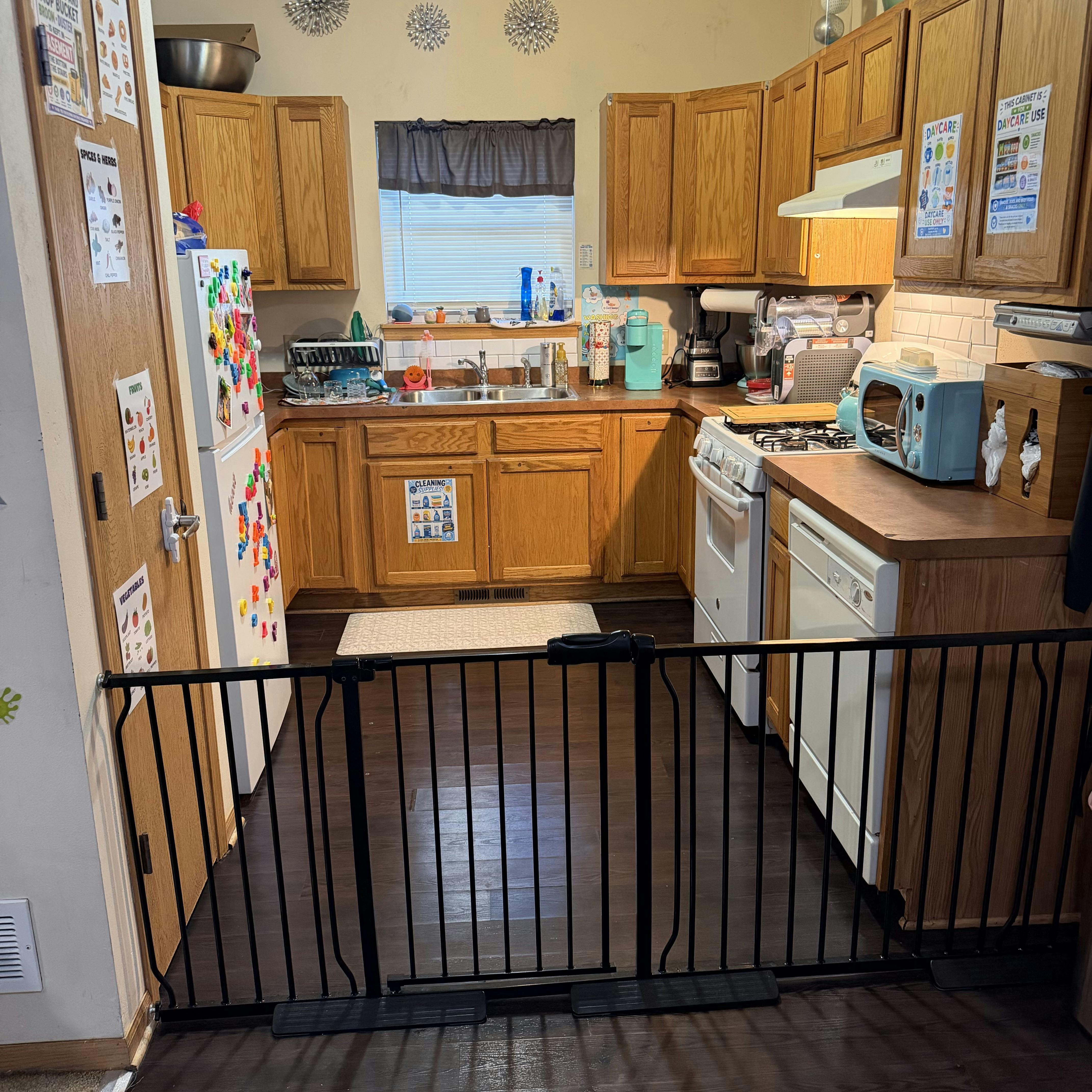 Kitchen with wooden cabinets and a child safety gate across the entrance