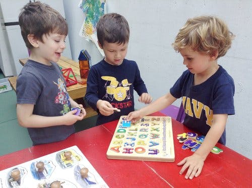 Three children playing with an alphabet puzzle