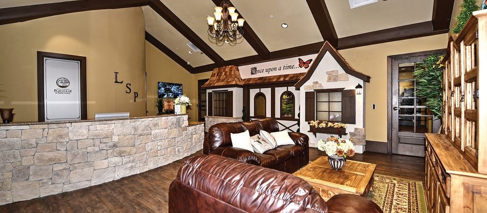 Lobby with a stone reception desk, leather couches, and a playhouse