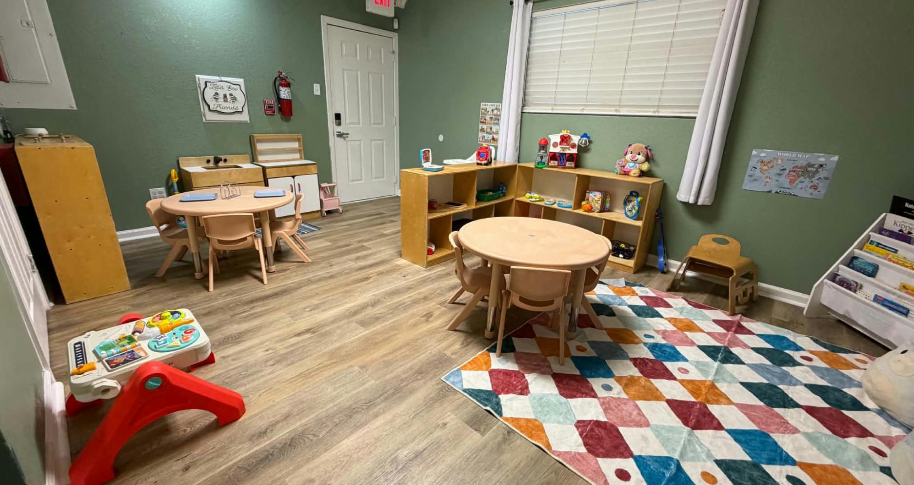 Childcare playroom with small tables, chairs, toys, and shelves