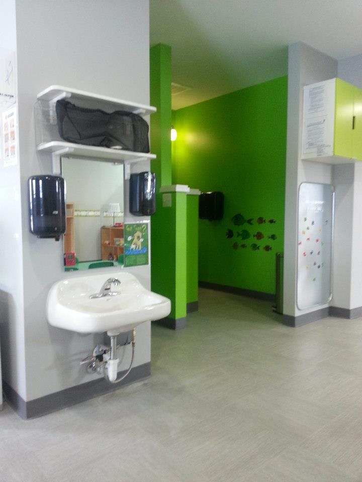 Sink with mirror and soap dispensers in a room with green walls