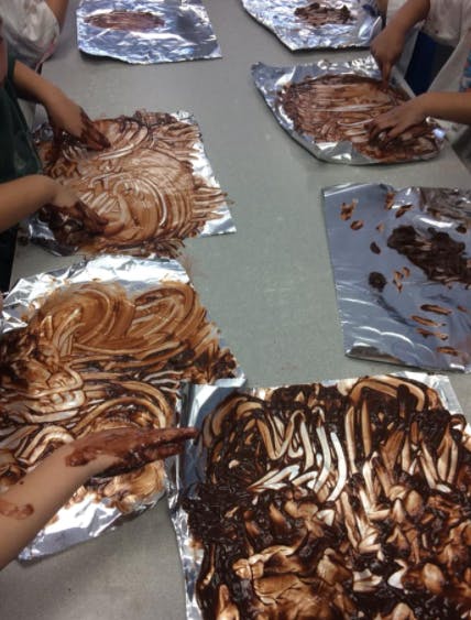 Children's hands covered in chocolate spread on foil