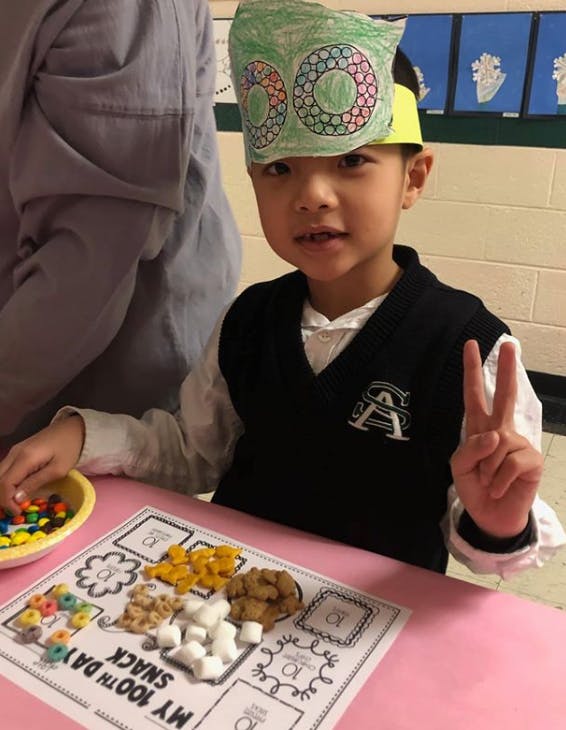 Child in a paper crown making a snack mix of snacks on a placemat