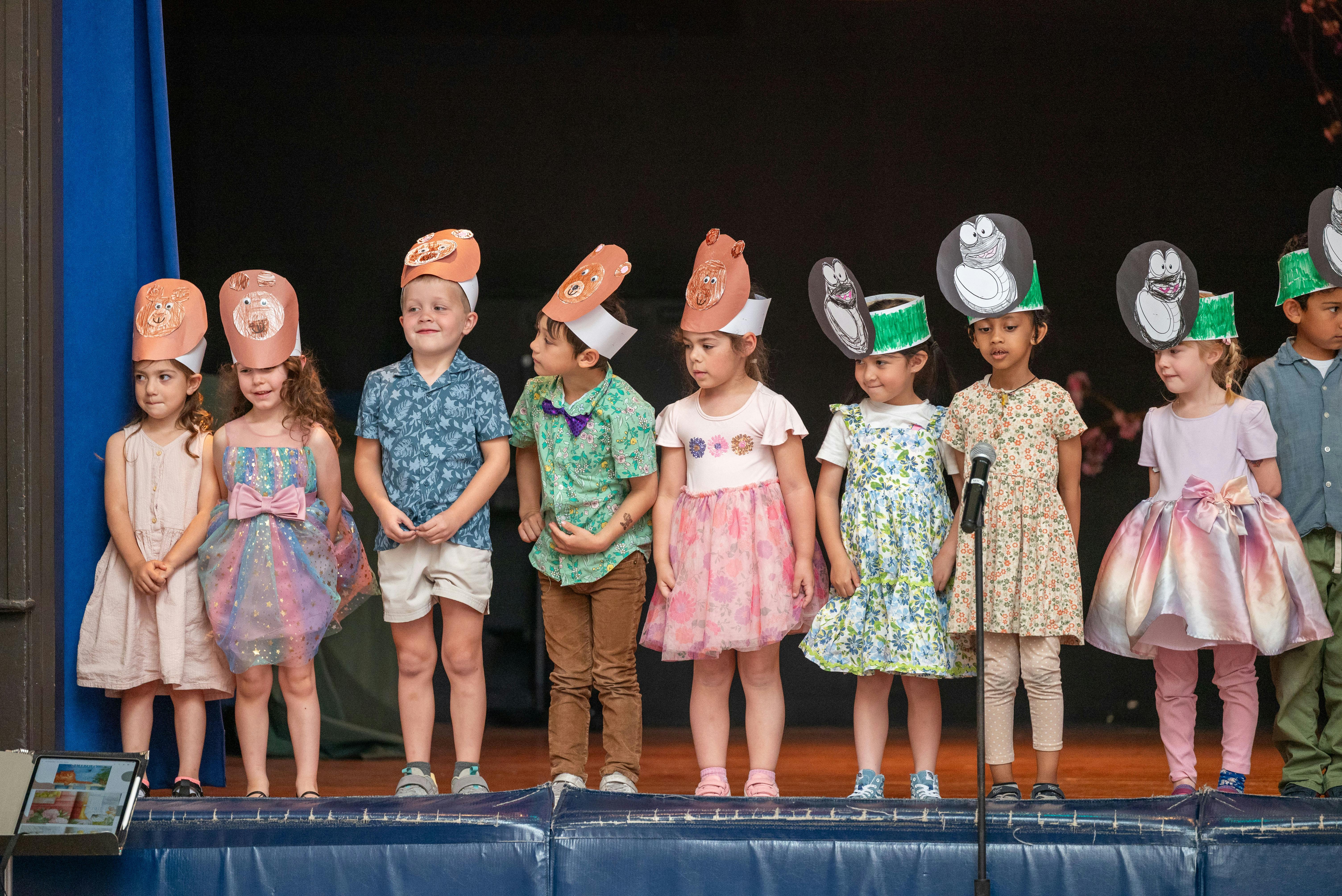 Children in costumes and hats standing on a stage
