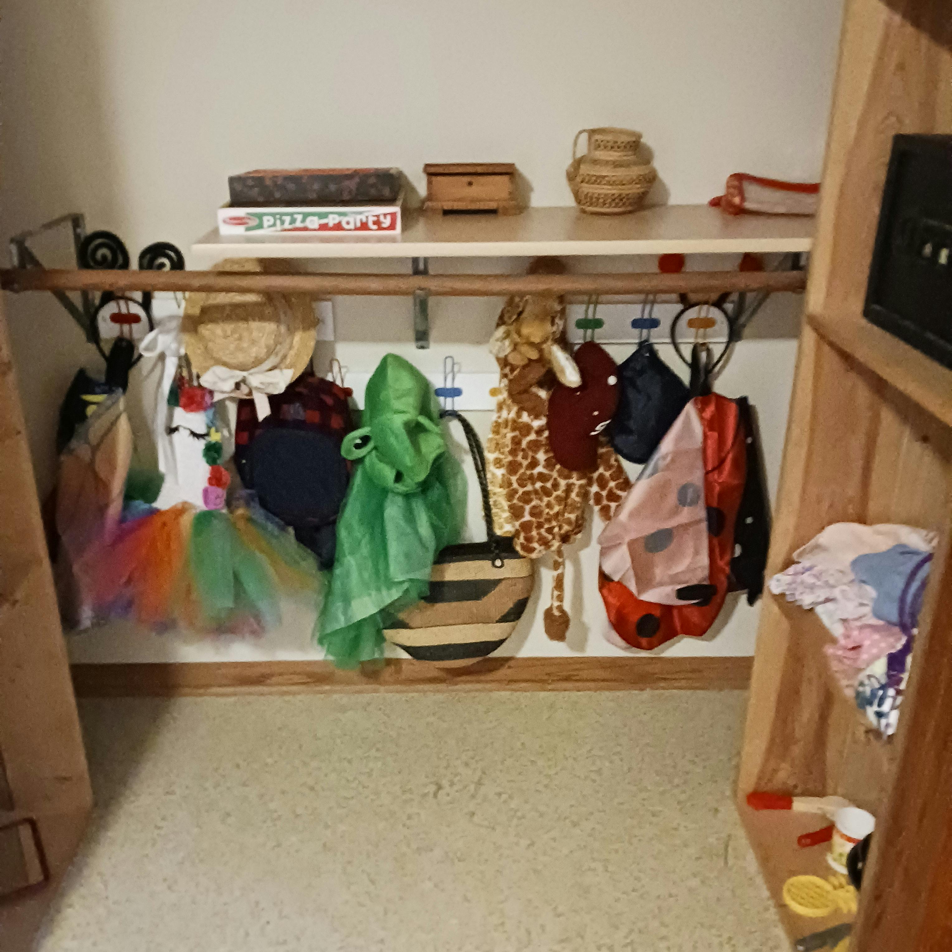 Costumes and accessories hanging on hooks below a shelf