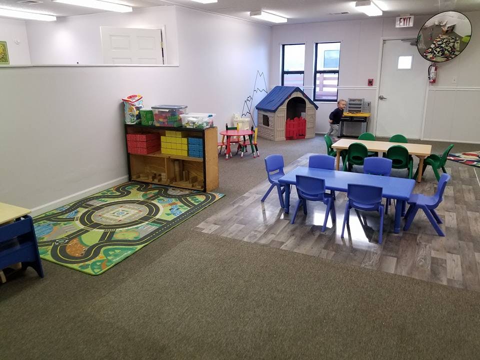 Playroom with small tables and chairs, a playhouse, and a rug
