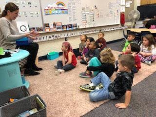 Adult speaking to children seated on floor in classroom