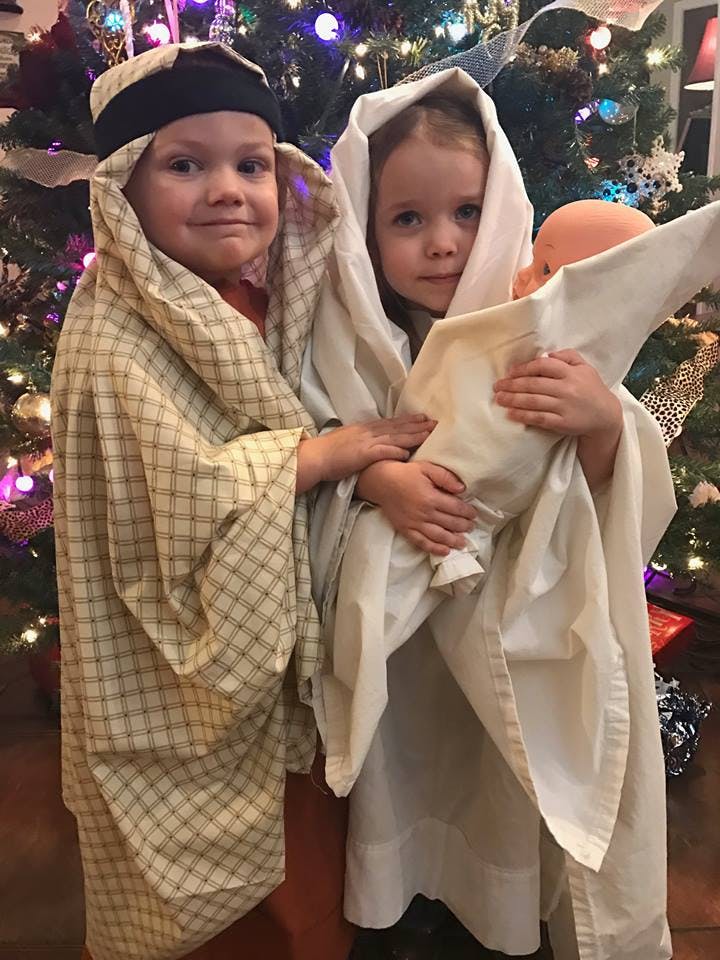 Two children in costumes, one holding a doll wrapped in cloth