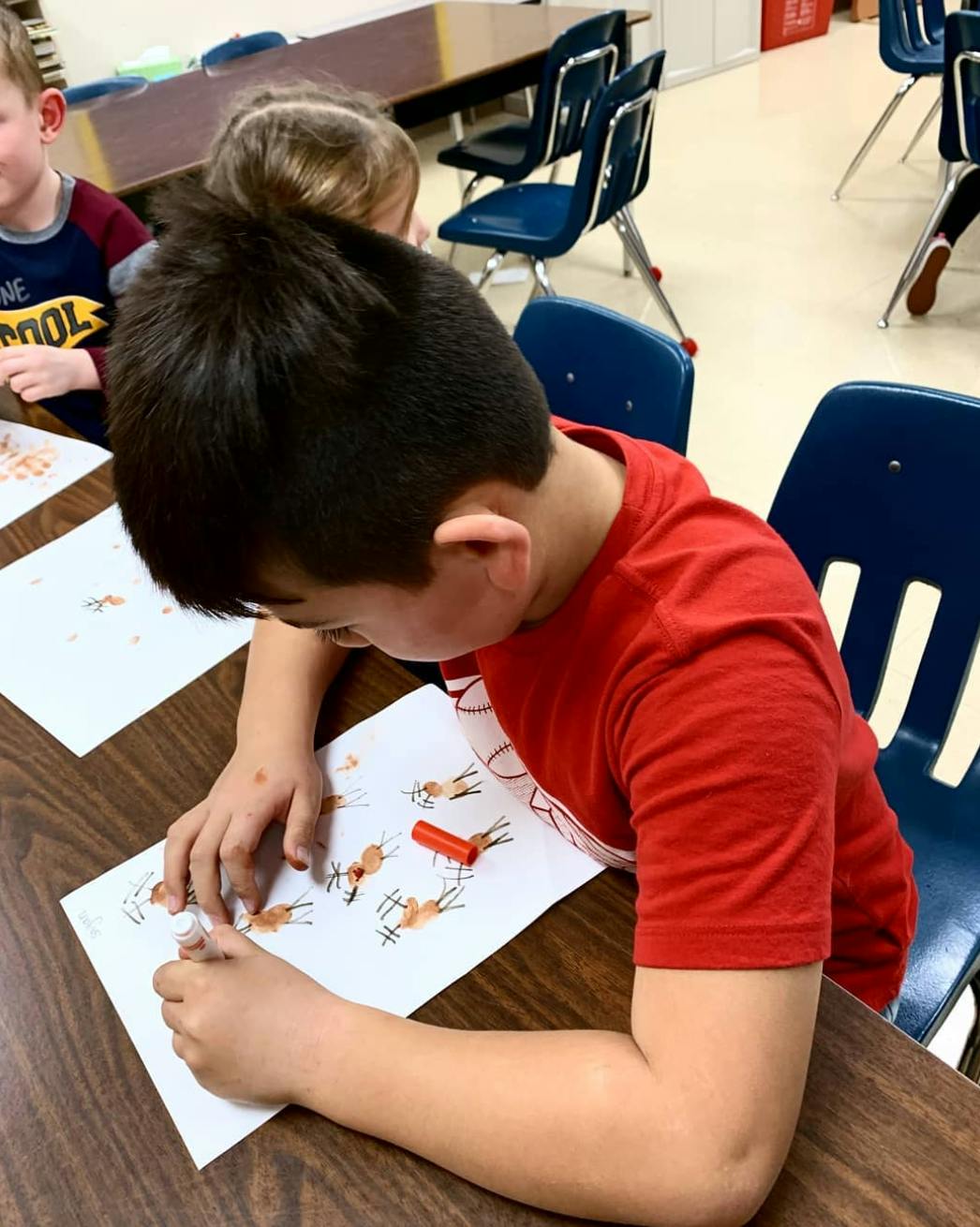 Child drawing on paper at a desk in a classroom