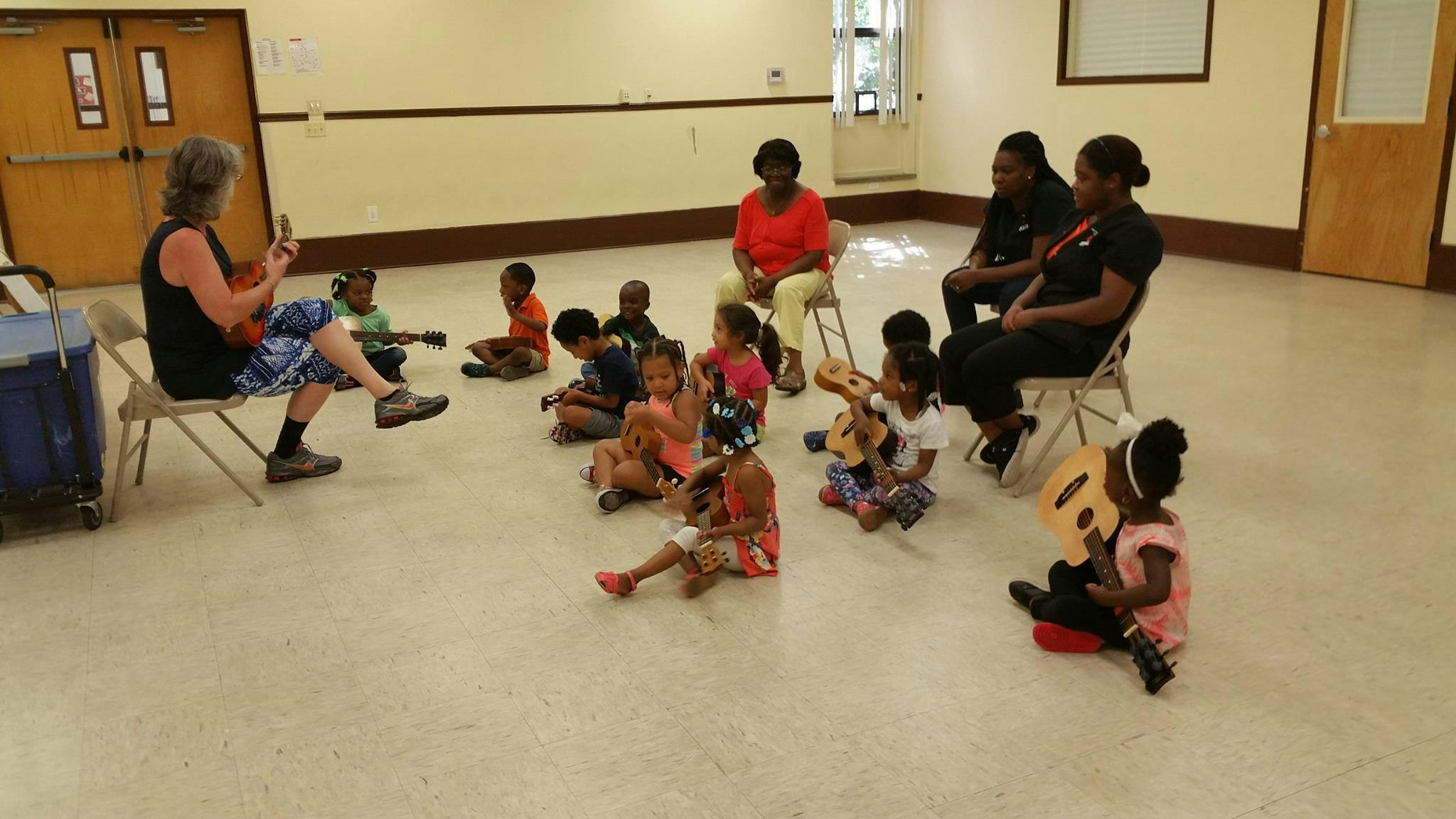Person playing guitar for a group of children and adults