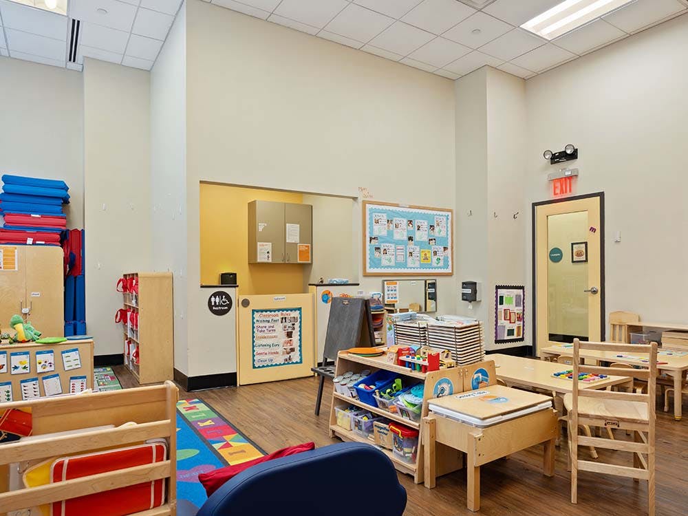 A classroom with small tables, chairs, and learning materials