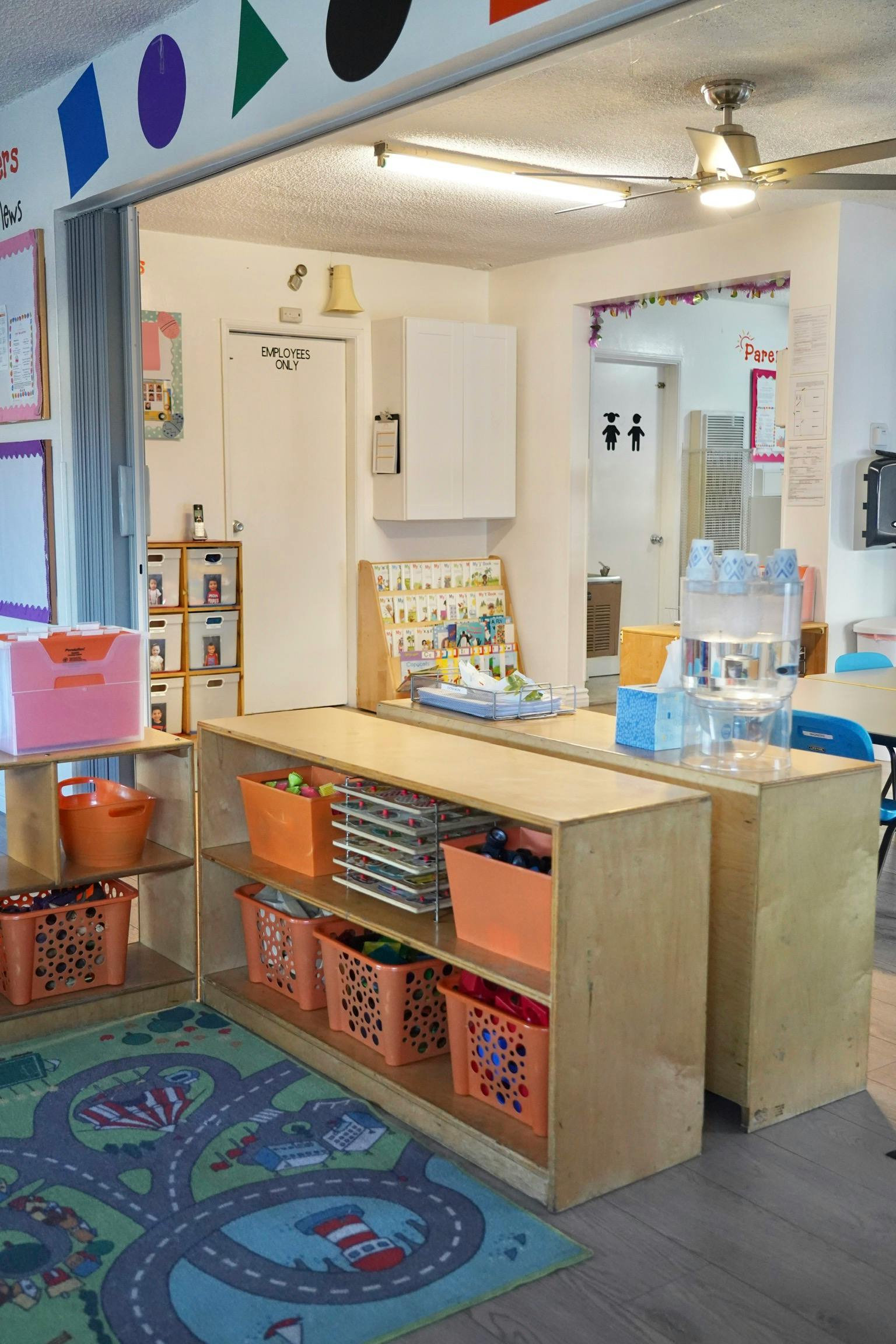 Classroom with shelves of orange baskets and a road map rug
