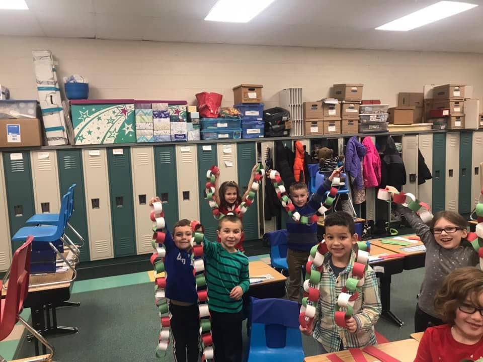 Children holding paper chains in a classroom