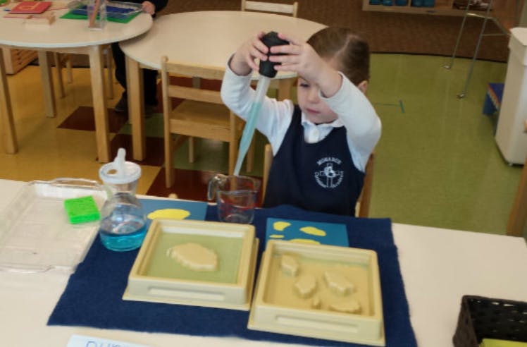Child using a dropper with liquid in a classroom