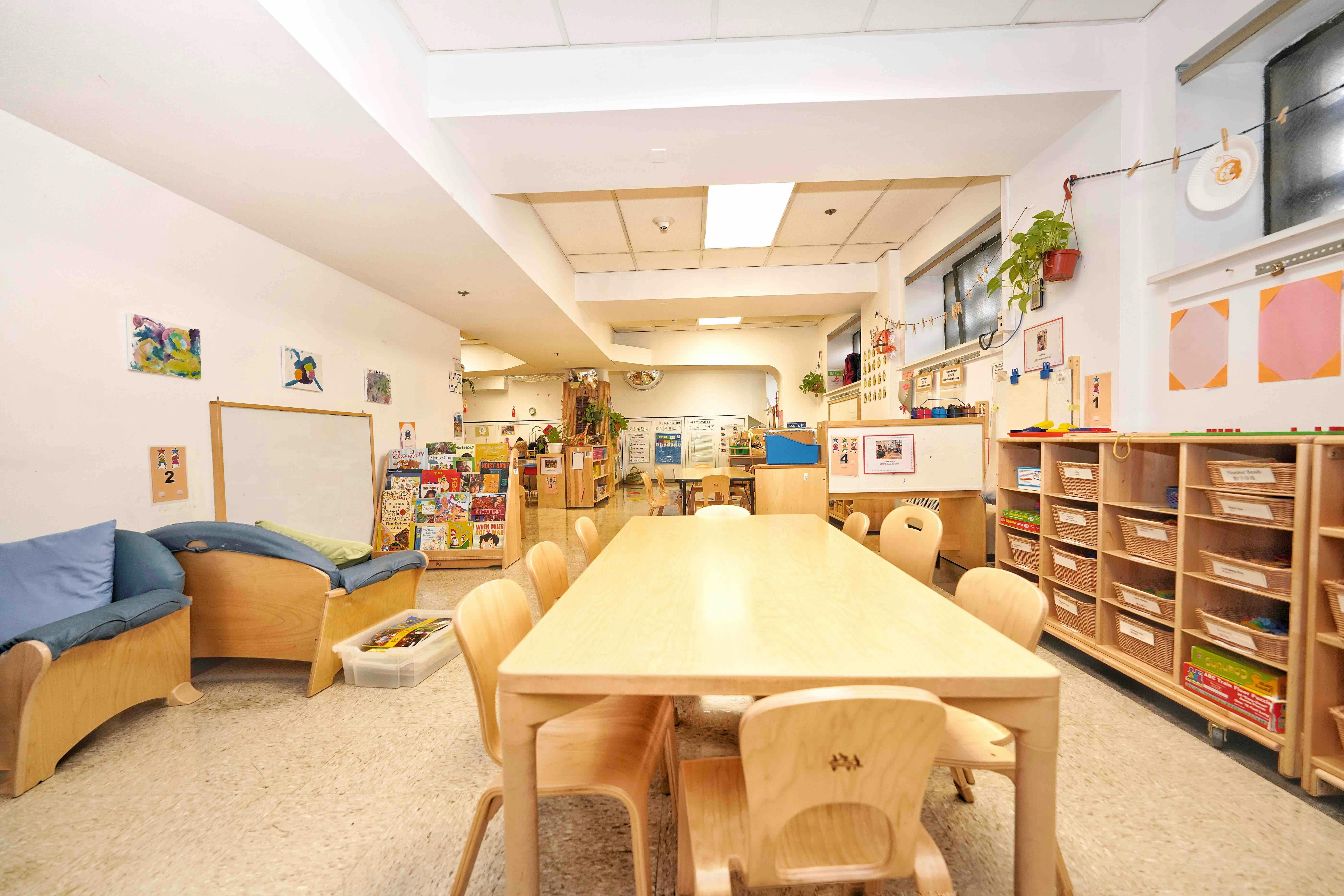 Classroom interior with a central wooden table and chairs and storage shelves