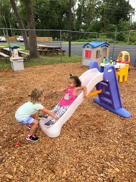 Two children playing on a slide on a playground
