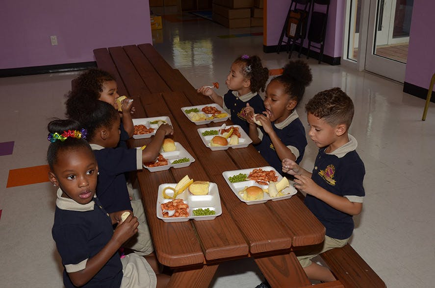 Children eating meals at a picnic table