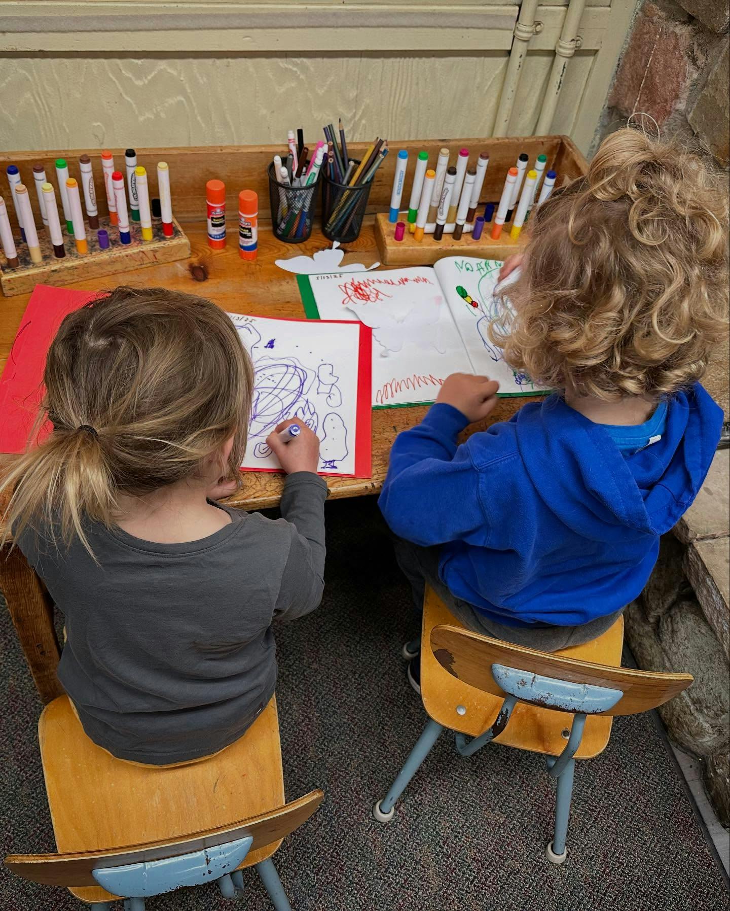Two children drawing at a table
