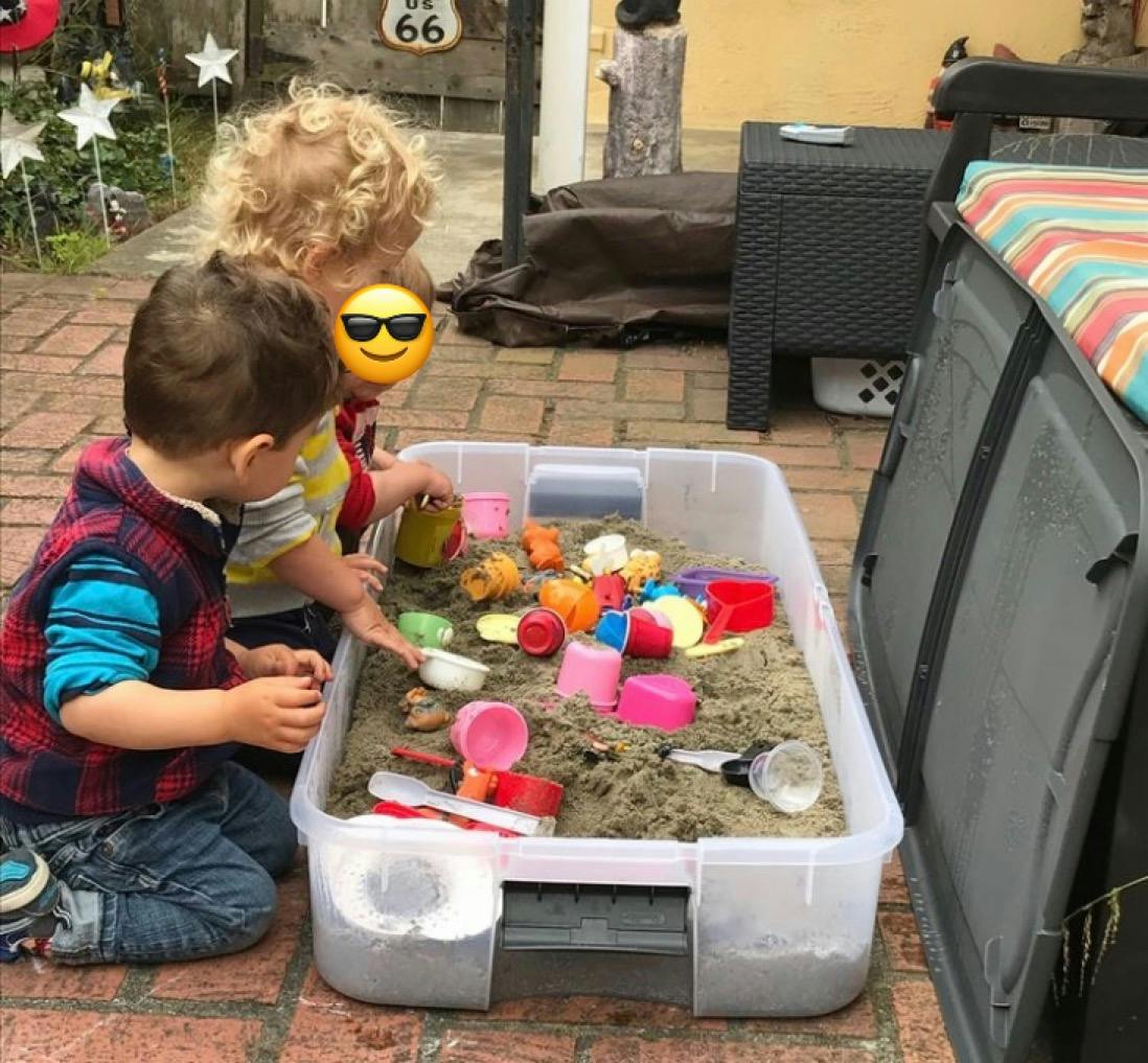 Two children playing in a sandbox with colorful toys