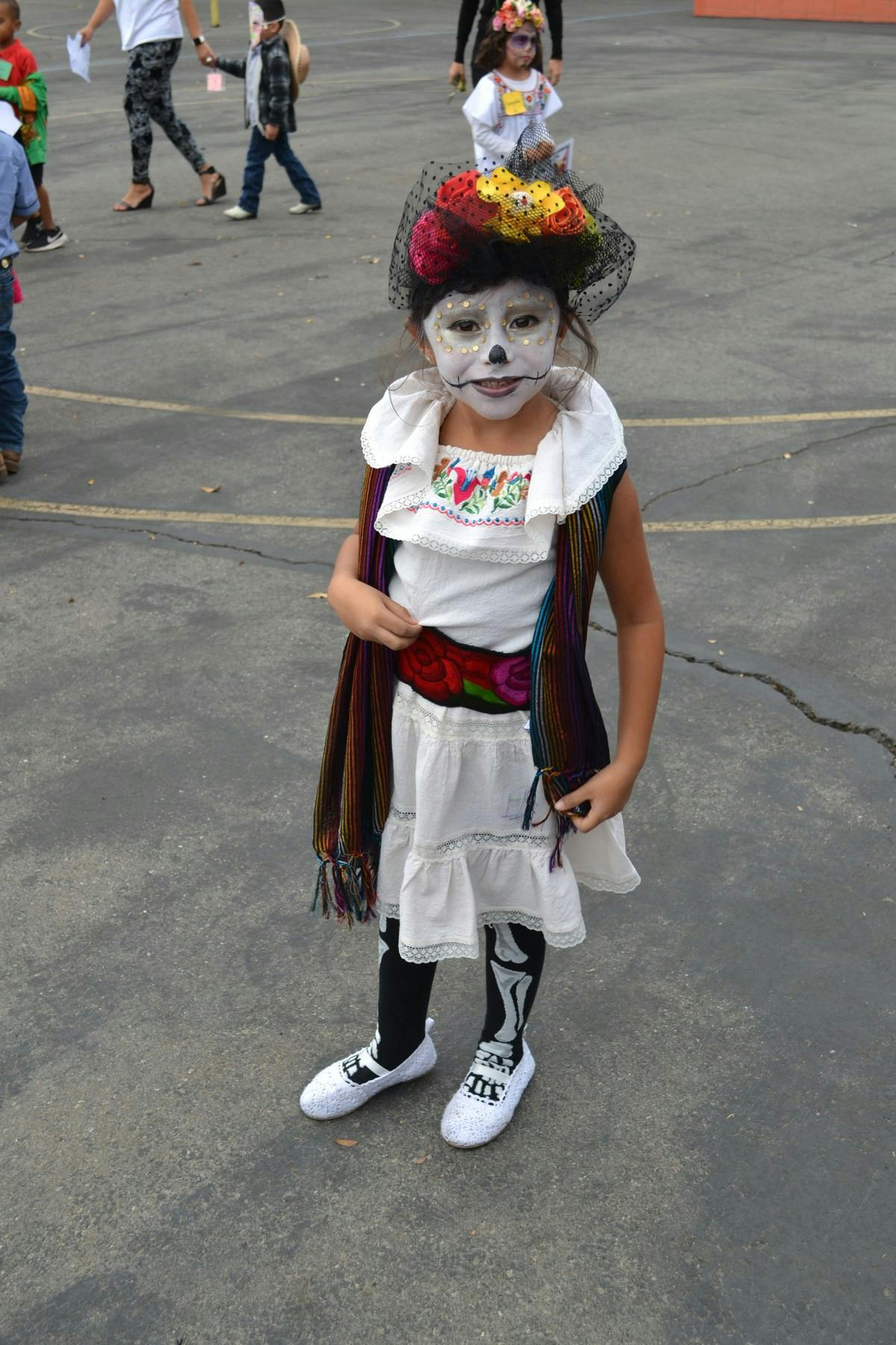 Child in a Day of the Dead costume with face paint and floral hat