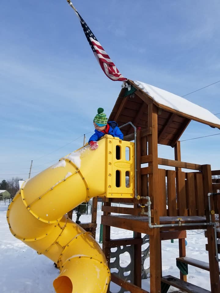 Child on a yellow slide on a snowy playground