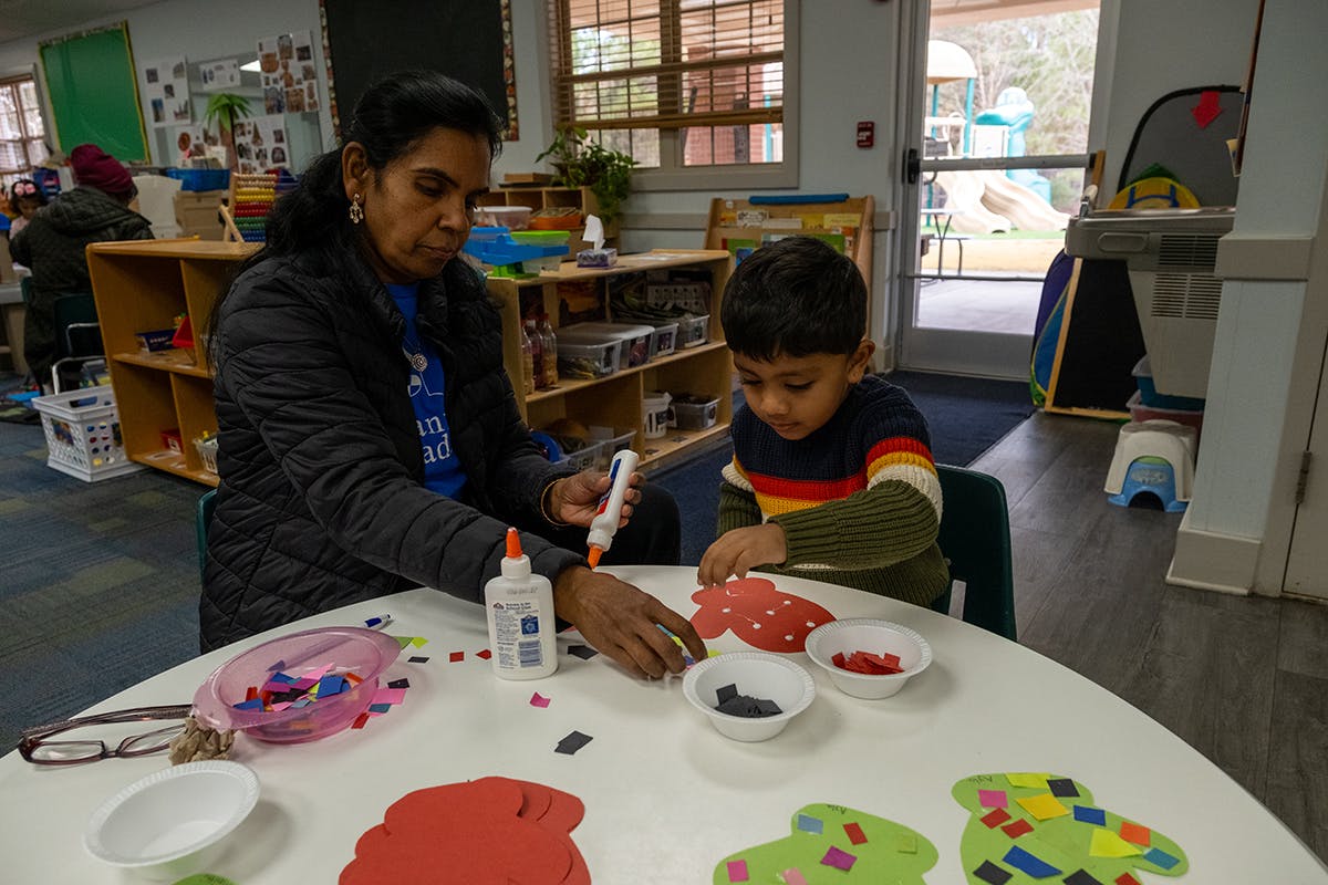 Person and child doing crafts at a table in a classroom