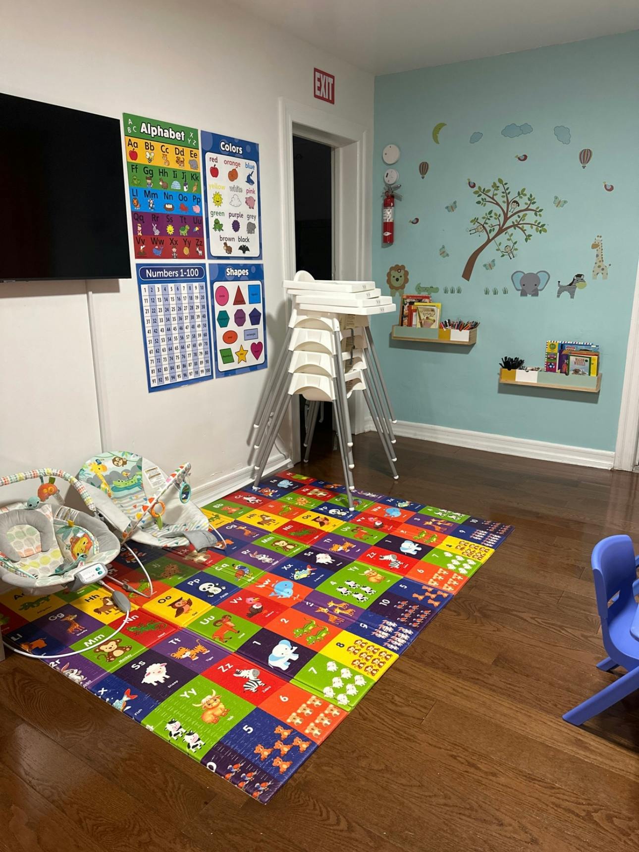 Playroom with colorful alphabet and number charts, playmat, and high chairs