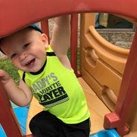 Child in a neon shirt playing on a playground structure