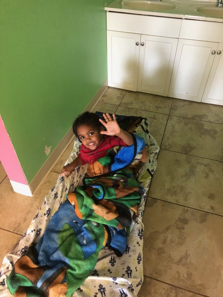 Child lying on a blanket, waving