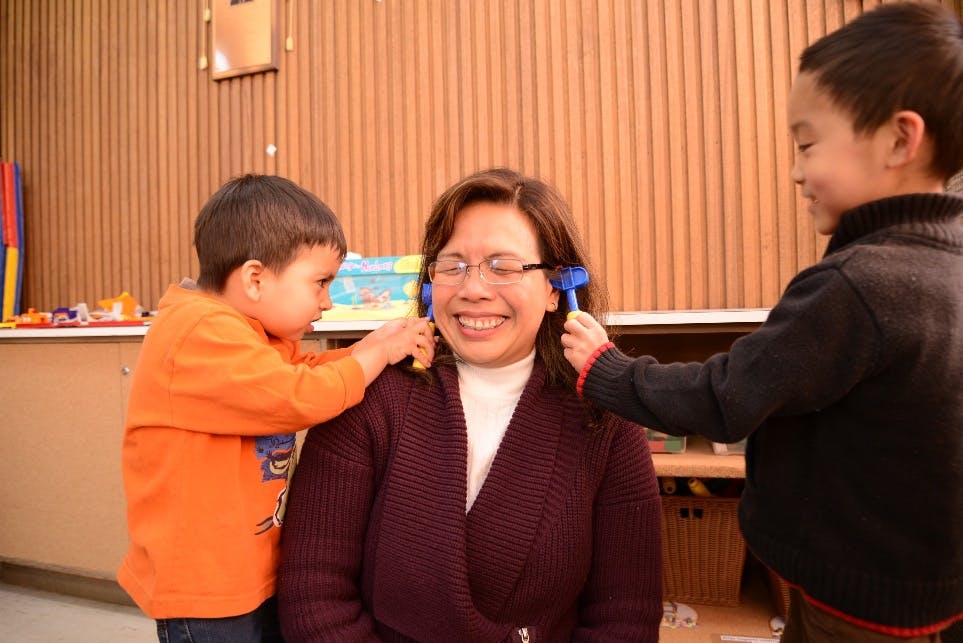 Person with two children playing with toy hammers on their head