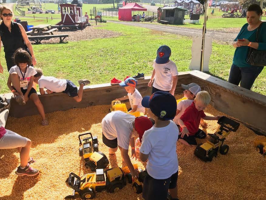 Children playing with toy trucks in a large sandbox