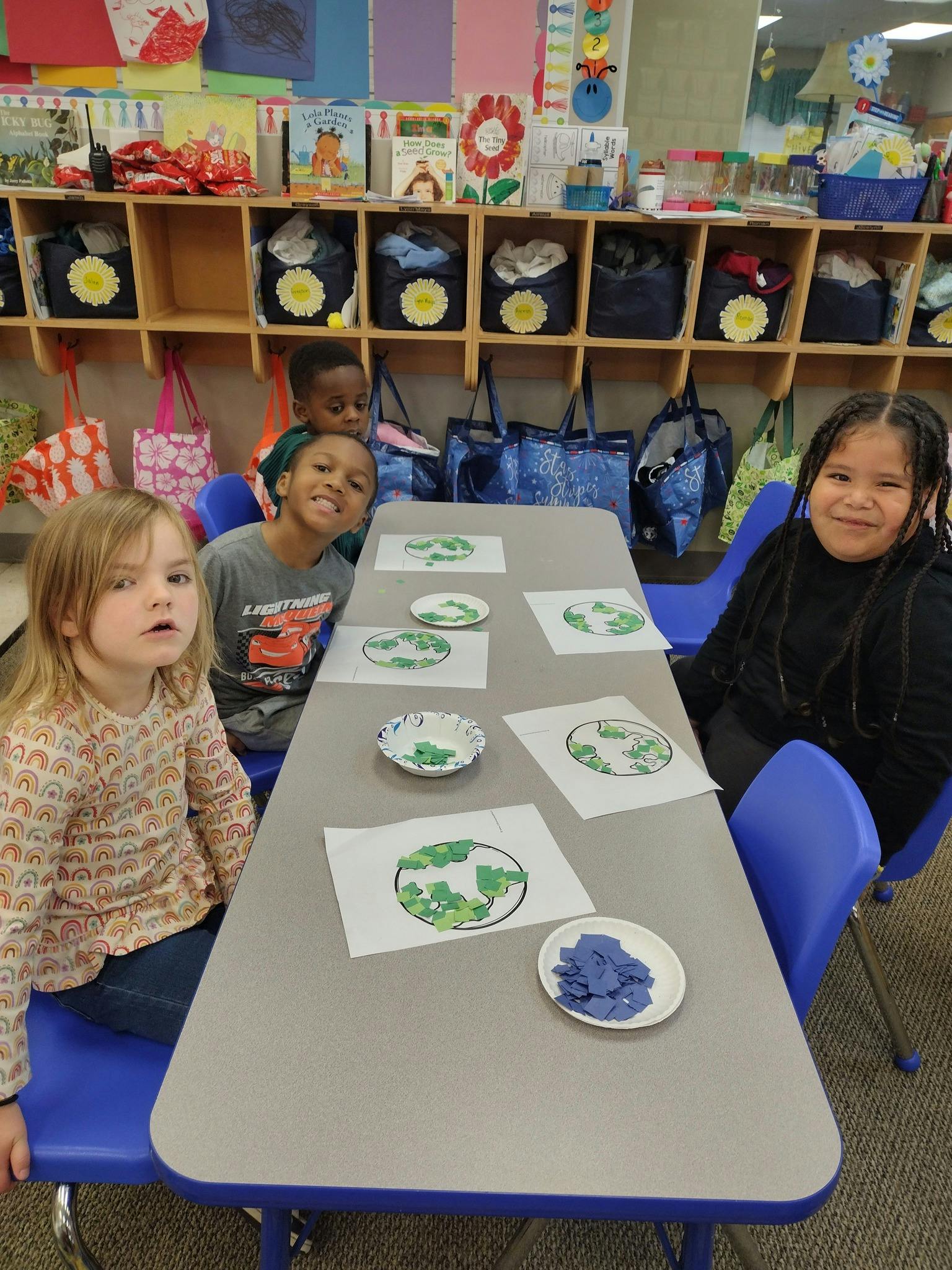 Three children at a table with craft supplies in a classroom