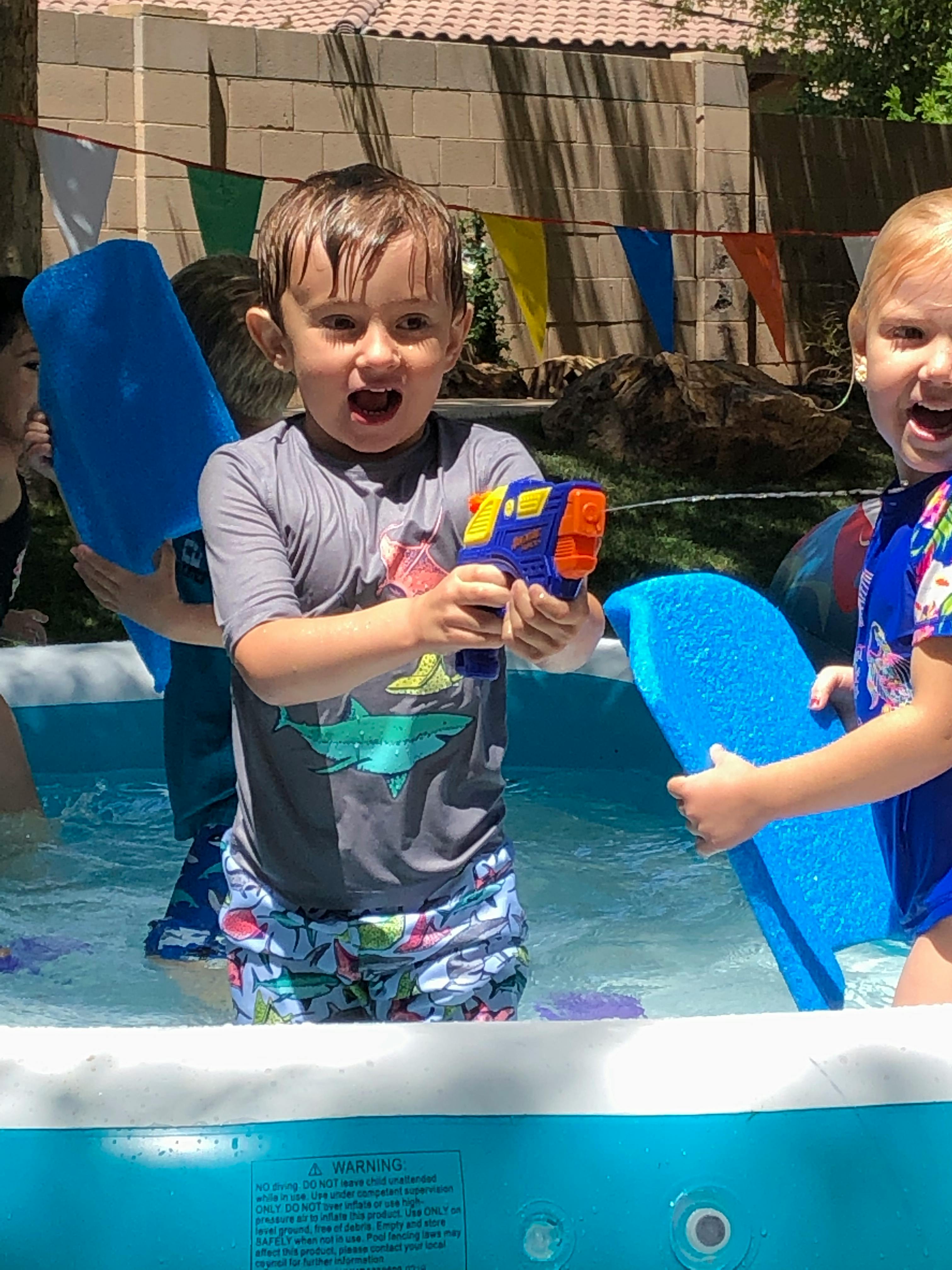 Child holding a water gun in a pool