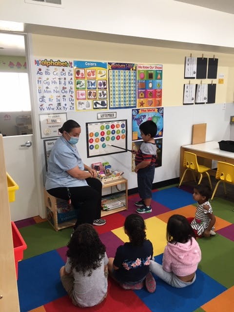 Person in mask teaching children in a classroom