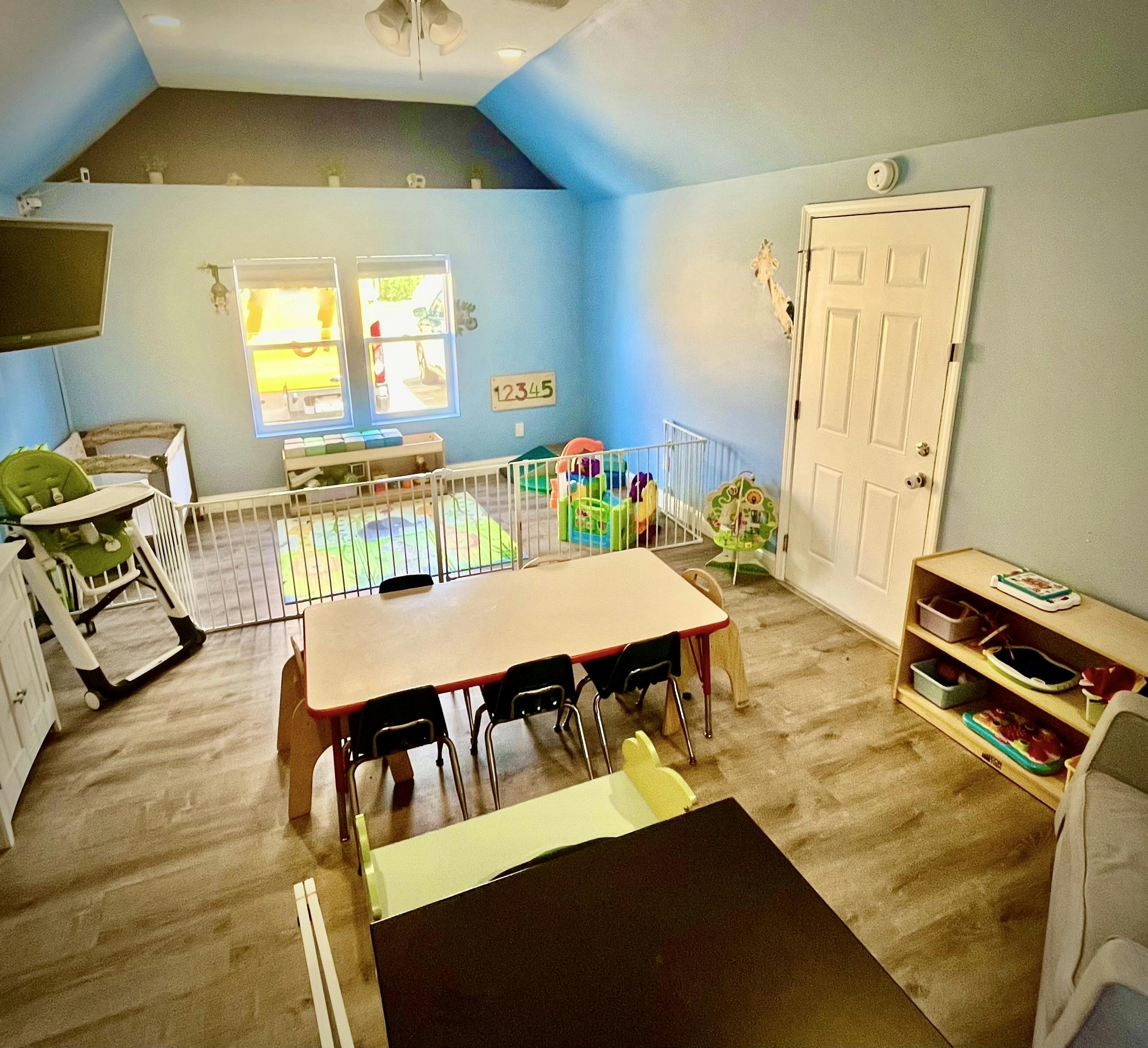 Playroom with small tables and chairs, playpen, and high chair