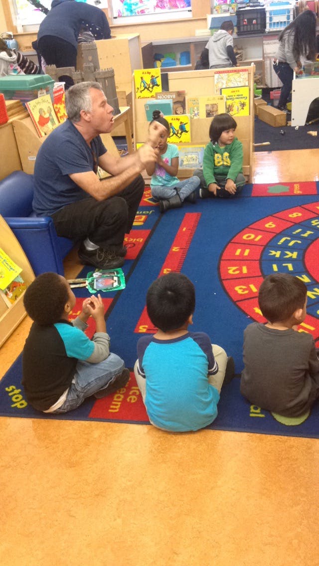 Adult and children sitting on a rug in a classroom