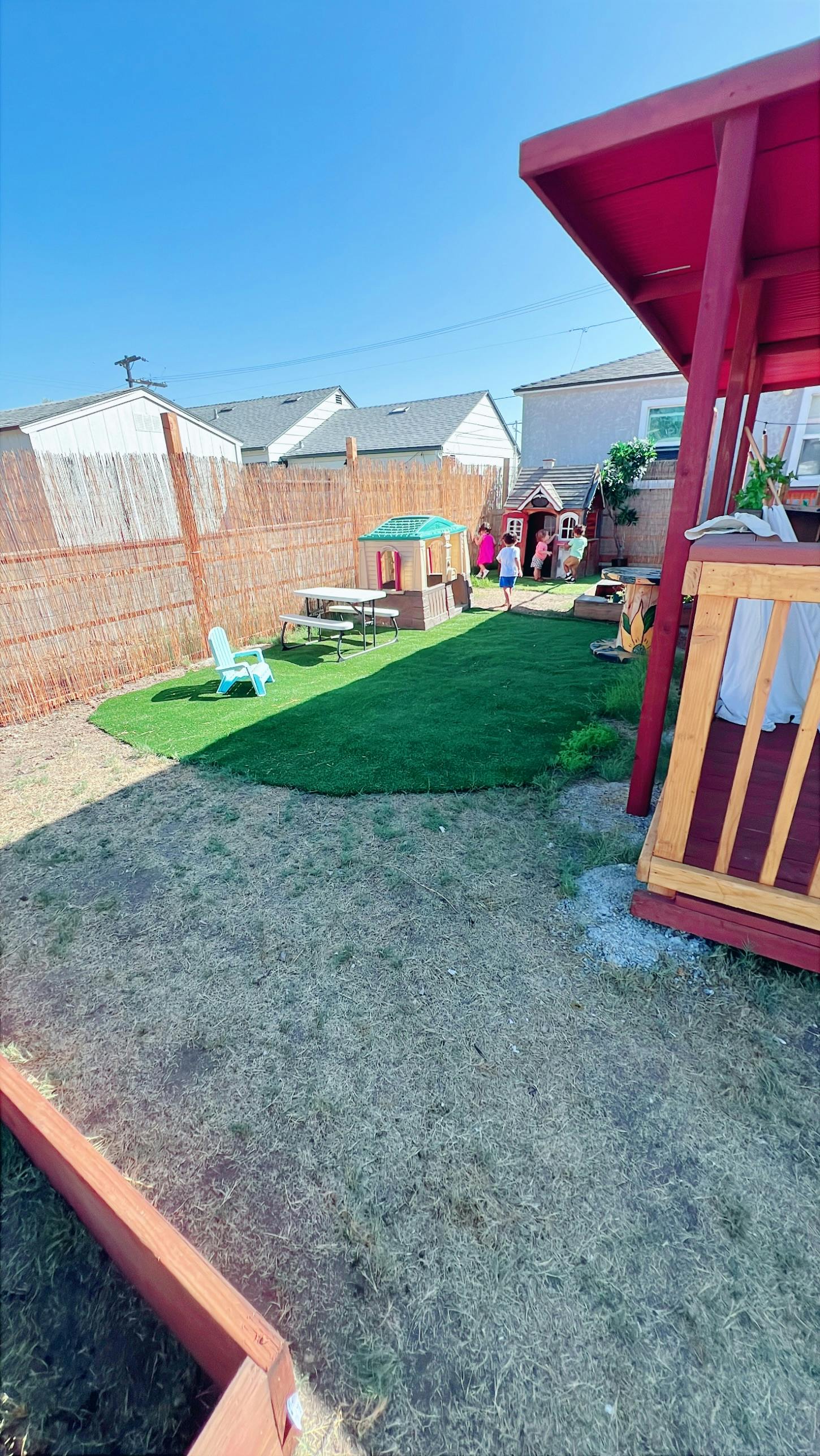 Backyard with artificial turf, playhouse, and children playing
