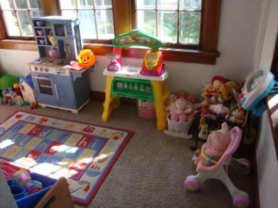 Children's play area with toy kitchen, market stand, and rug