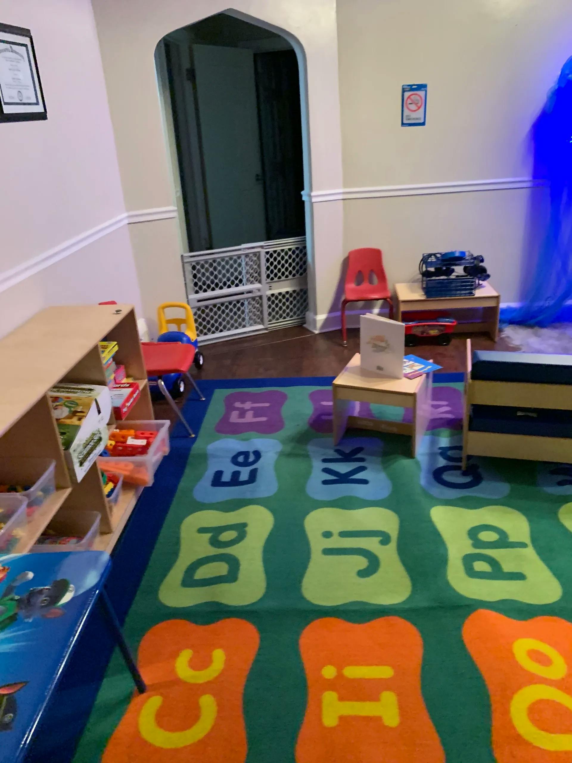Playroom with alphabet rug, small tables, chairs, and toy storage