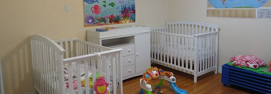 Two white cribs and a changing table in a room