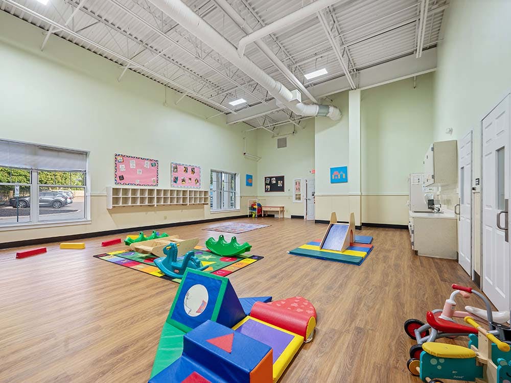 Playroom with soft play blocks, toy vehicles, and a small slide
