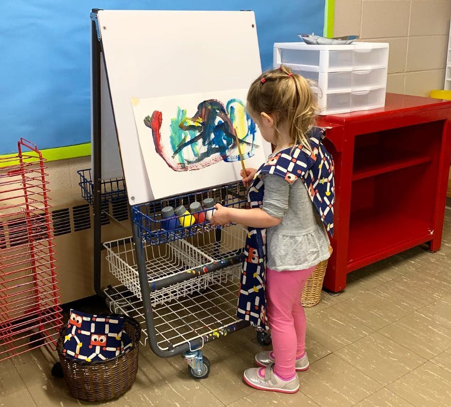 Child painting at an easel in a classroom