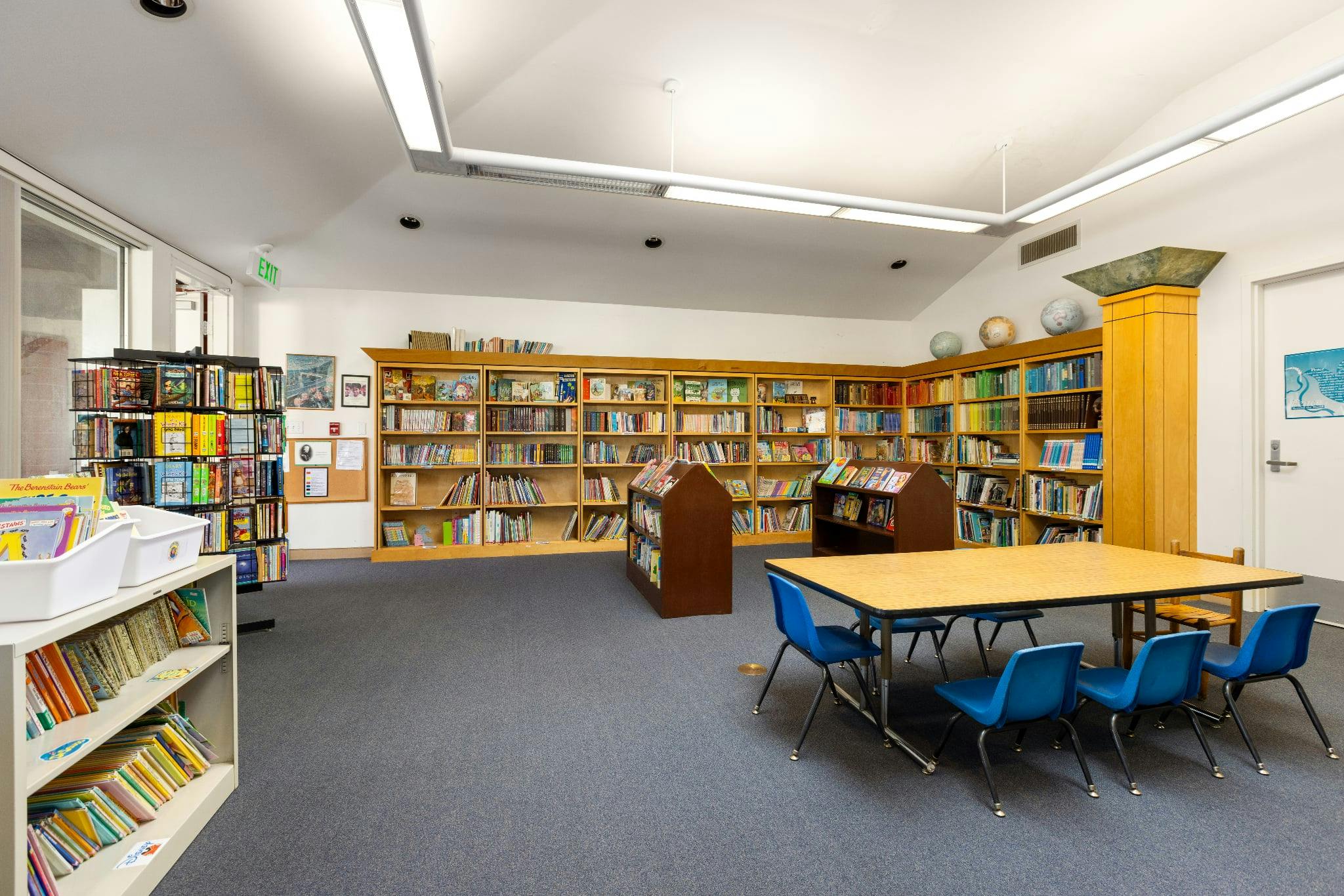 Children's library with bookshelves, small table, and blue chairs