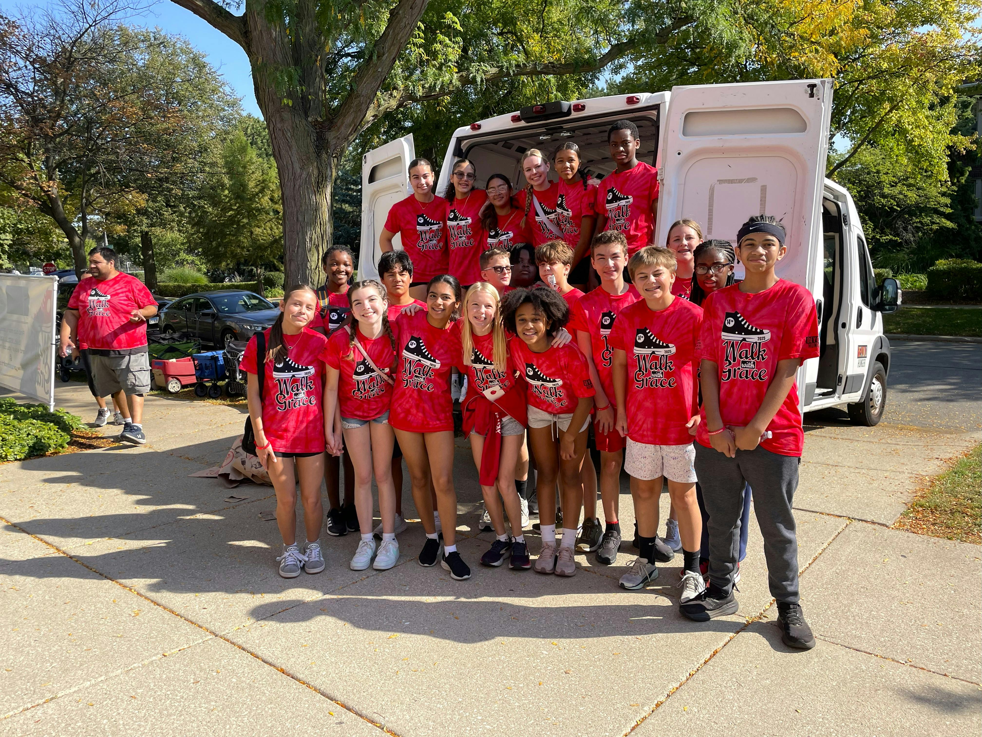 Group of teens and children in red shirts standing in front of a white van