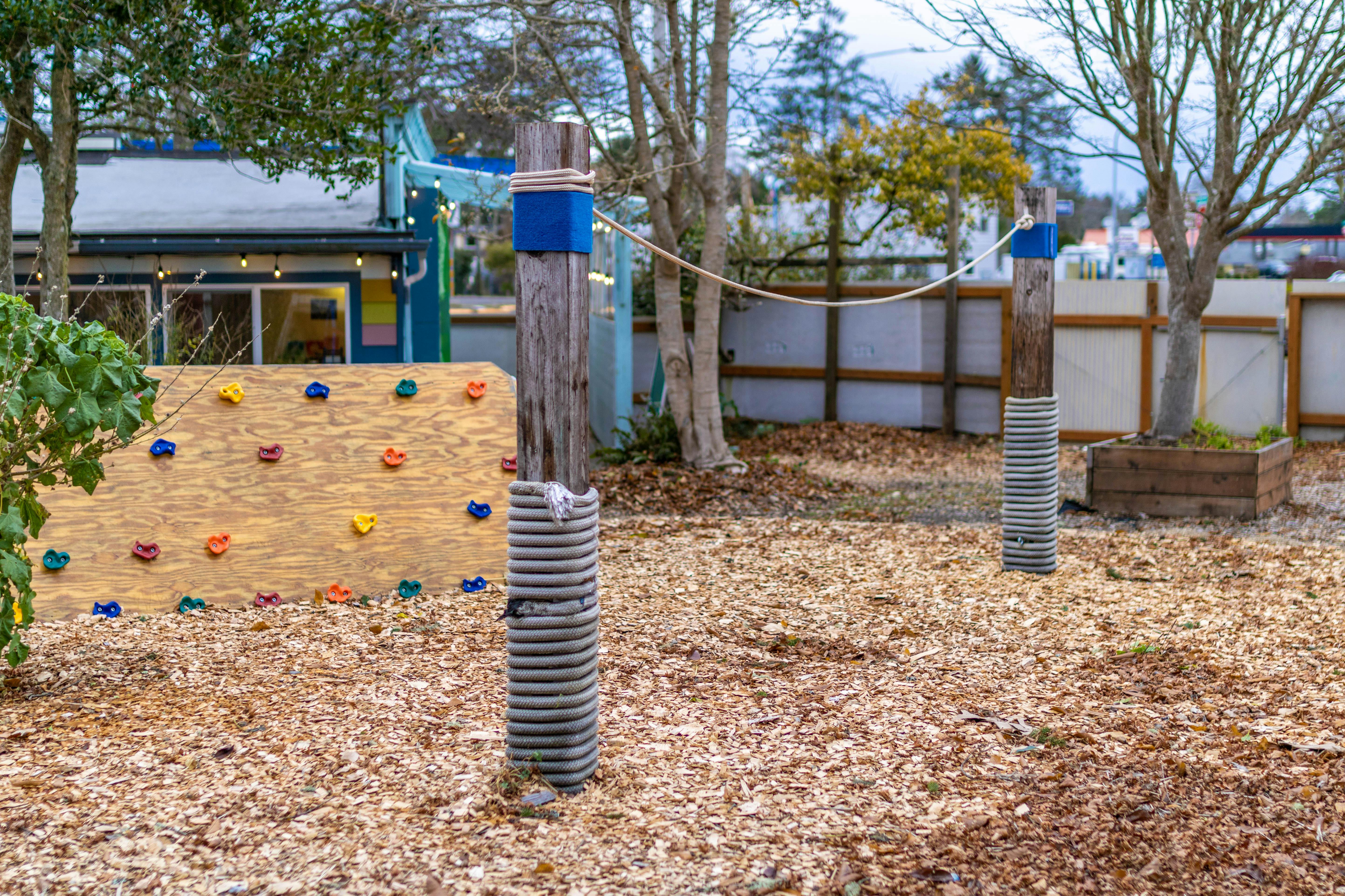 Outdoor play area with a climbing wall and wooden posts