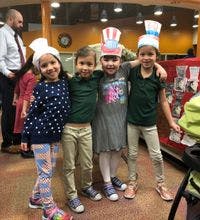 Four children wearing paper hats standing together